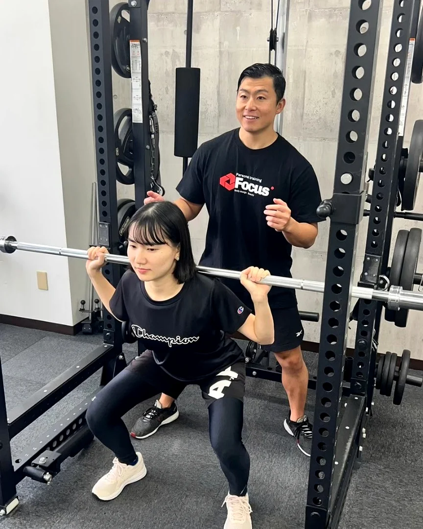 トレーナーがスクワットフォームを確認する様子