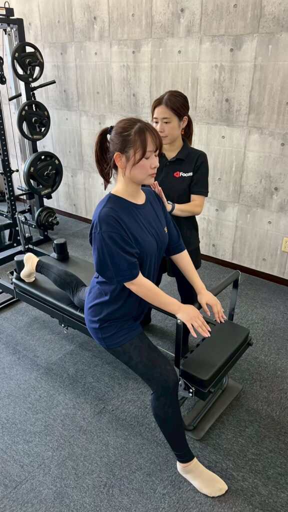 Personal training Focus.で女性トレーナーがピラティスリフォーマーの動作を確認している様子